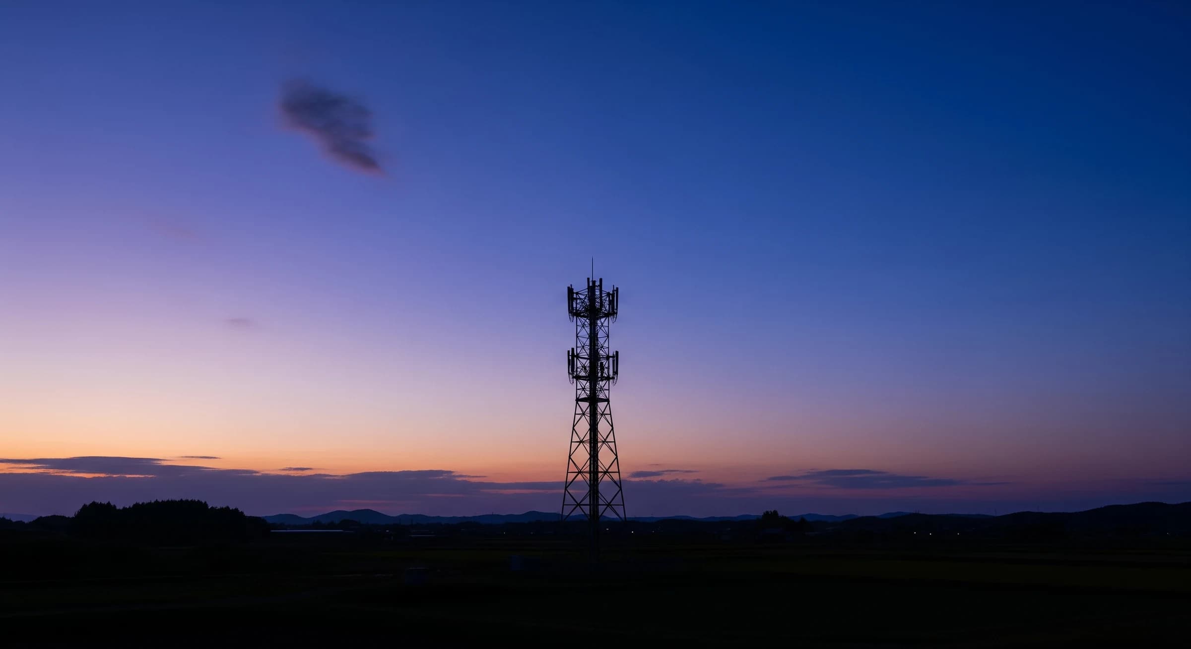 夕暮れに浮かぶ携帯電話基地局の鉄塔